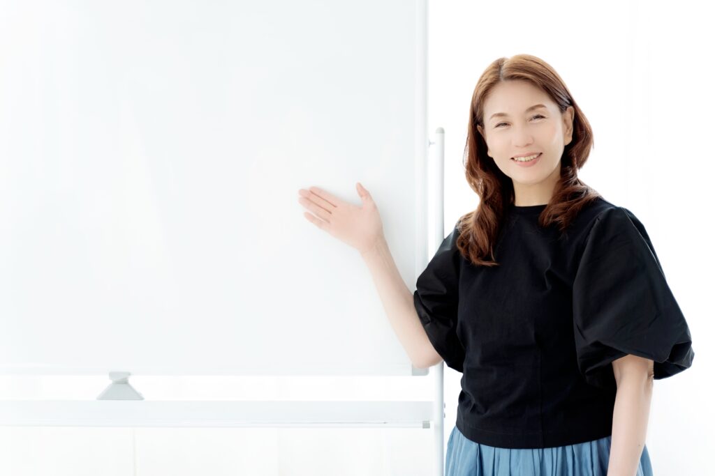 A woman pointing at a whiteboard with a smile